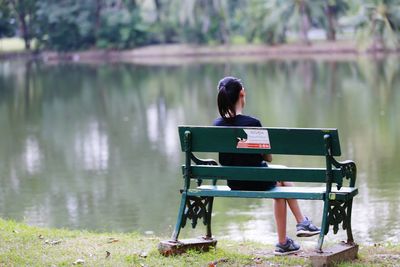 Rear view of woman sitting by lake