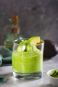 Green smoothie from avocado and cucumbers in a glass on the table vertical view