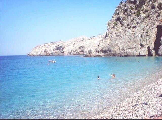 sea, water, leisure activity, beach, blue, lifestyles, scenics, vacations, beauty in nature, mountain, tranquility, clear sky, tranquil scene, nature, rock formation, men, horizon over water, rock - object, shore