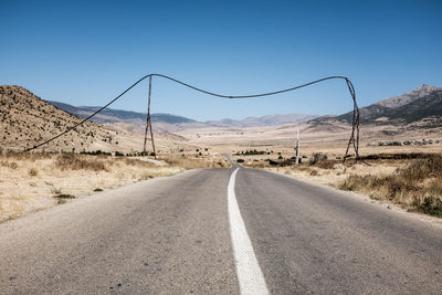 Empty road by landscape against clear sky