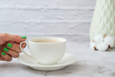 Manicured female hands with stylish green nails holding cup of coffee. take a break for coffee latte