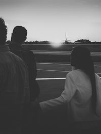 Rear view of couple sitting on car against sky