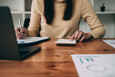 Midsection of businesswoman working on table