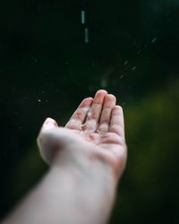 Rain falling on cropped hand