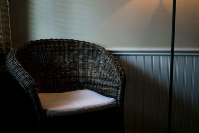 Close-up of empty chair against wall at home