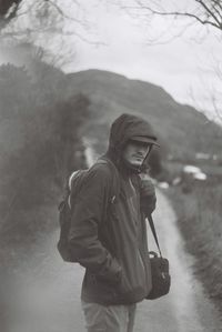 Portrait of young man standing on road during winter