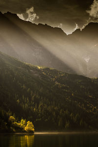Sunlight falling on mountains and lake during foggy weather
