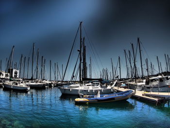 Boats moored at harbor against blue sky