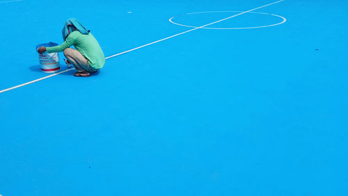 Side view of man making lines on sports court