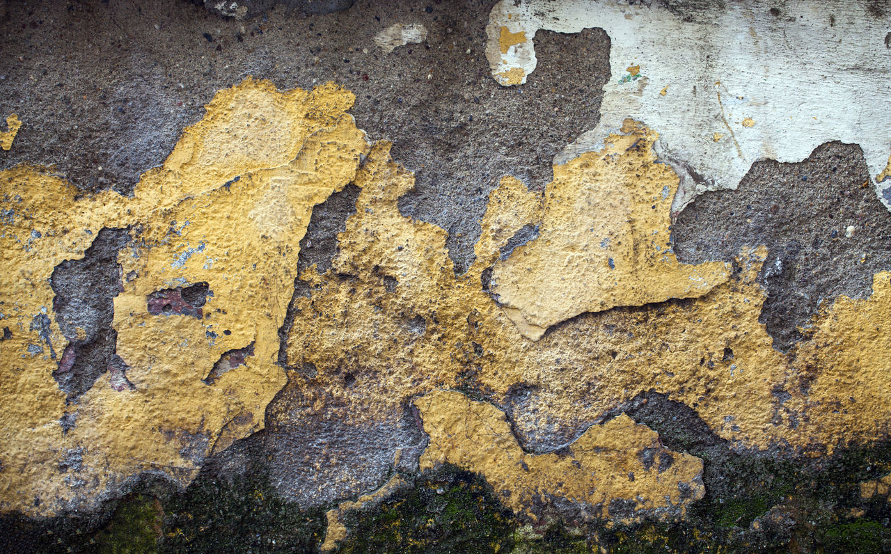 FULL FRAME SHOT OF WEATHERED WALL WITH YELLOW PAINT ON CONCRETE