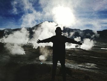 Silhouette man with arms outstretched standing on field