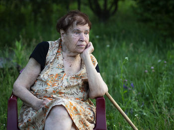 Thoughtful senior woman sitting on chair in back yard