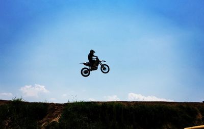 Low angle view of man riding motorcycle on field against sky
