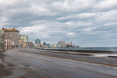 Road by buildings against sky in city