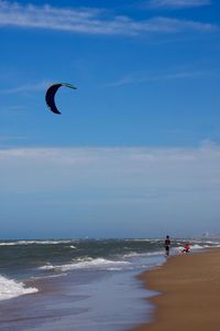 People on beach by sea against sky