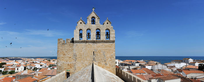 Old building by sea against blue sky