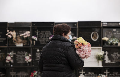 Old lady with mask mourning her family in cemetery. almeria, spain