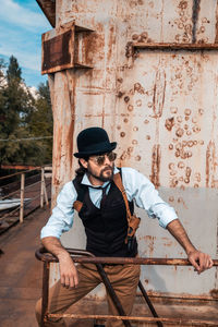 Man looking away while sitting on wood