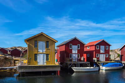 Boats moored on canal by building against blue sky