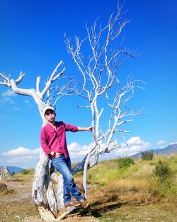 Full length of man standing on field against blue sky