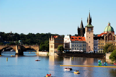 Bridge over river by buildings against sky