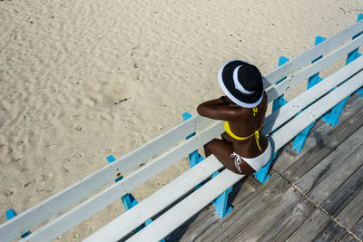 High angle view of woman sitting on bench at beach
