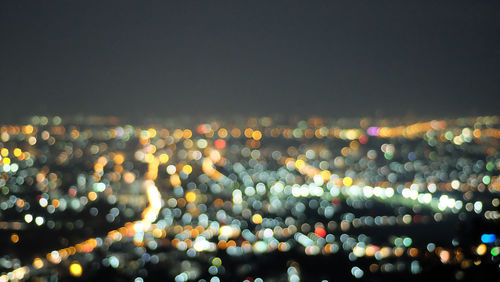 Defocused image of illuminated city against sky at night