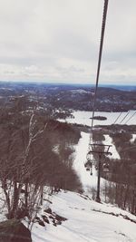 Ski lift over snow covered mountains against sky