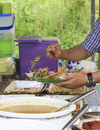 Cropped hands of man serving food in plate