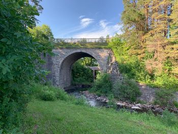 Arch bridge amidst trees against sky