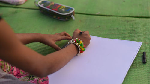 Cropped hands of girl drawing on paper