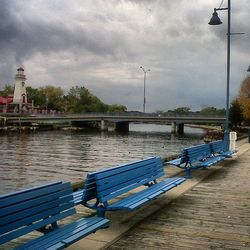 Bridge over river against cloudy sky