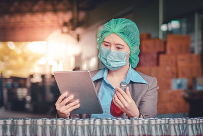 Woman using digital tablet while inspecting drinks in factory