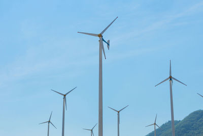 Low angle view of wind turbines against sky