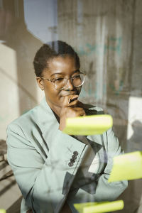 Creative businesswoman looking at adhesive note in creative office