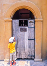 Rear view of boy knocking wooden door