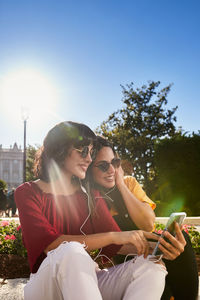 Young man using smart phone while sitting outdoors