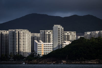 Buildings by sea against sky