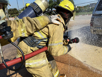 Firefighter spraying water on car outdoors