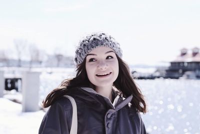 Portrait of smiling young woman against snow