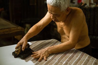 Side view of man using batik stamp to make the original batik cap