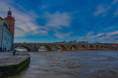 Arch bridge over river against buildings