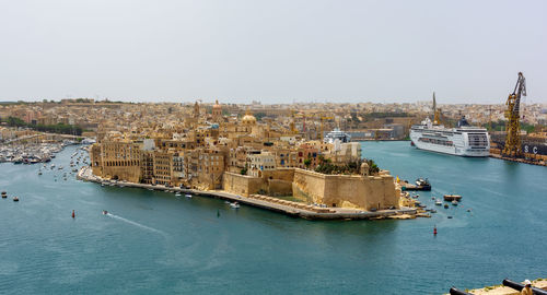 High angle view of buildings by sea against clear sky