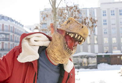 Man wearing dinosaur mask standing in city