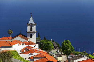 High angle view of church in city by sea against blue sky