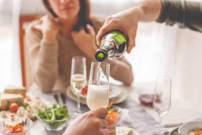 Close-up of man pouring drink with woman sitting on table at home