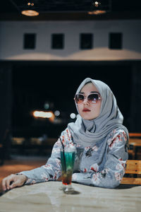 Portrait of young woman sitting on table