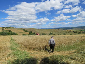 Rear view of man walking on field against sky