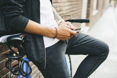 Teenager with a bike in the city, using smartphone