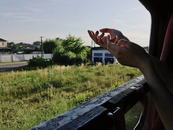 Close-up of hand holding car against sky
